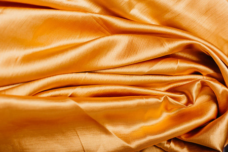 在褶皱的金色织物。帷幔。在丝绸上闪闪发亮。缝纫