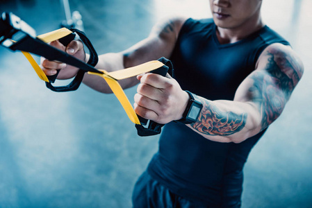 在健身房用阻力带训练年轻肌肉运动员的观点照片