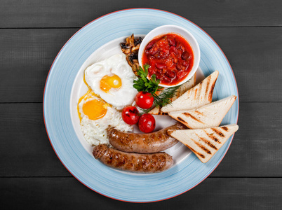 英国早餐油炸鸡蛋, 豆类, 香肠, 烤西红柿, 蘑菇, 烤面包和酱在盘子上的深色木质背景。健康食品, 高档景观, 平躺