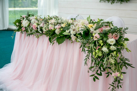 美丽的白色餐桌为新婚夫妇装饰与绿色和长布。长花排列的绣球花, 玫瑰, 百合, 百合和绿叶在白色的背景