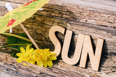 词太阳是由木信件在老木头背景用鸡尾酒伞。旅游, 休息, 度假, 海洋, 太阳, 海滩概念理念