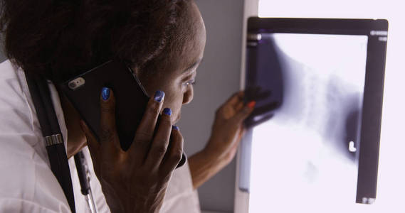 非洲资深女医生通过手机与同事讨论 x 光片