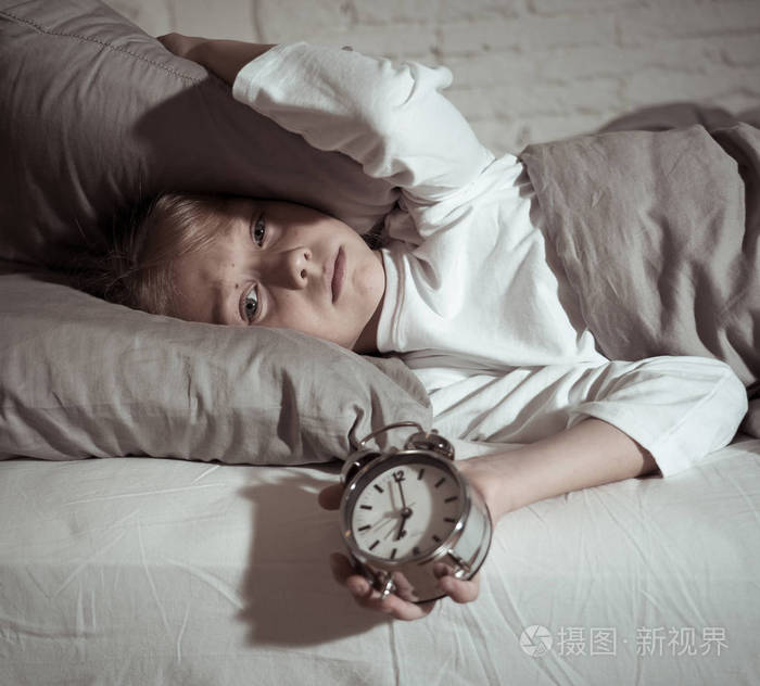 可爱的不眠之夜的小女孩在床上醒着, 在半夜看起来很累, 晚上不睡觉