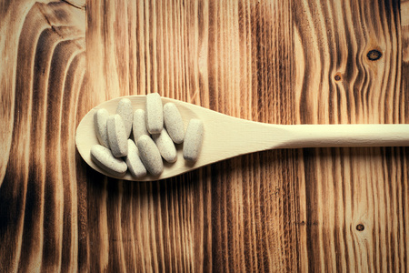 维生素或补剂在木勺老式木制板上