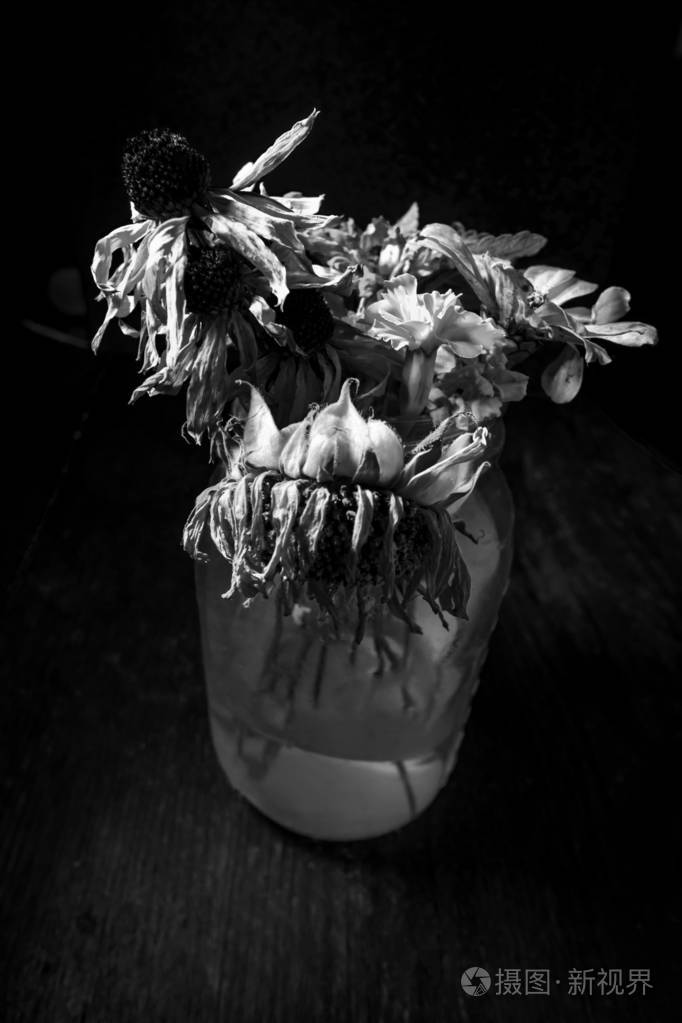 老枯萎的夏天的花在一个玻璃石匠罐子与黑暗的喜怒无常的照明