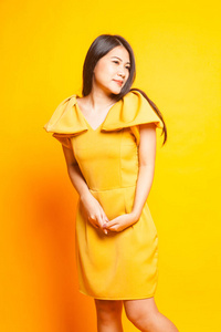 黄色背景的美丽的年轻亚洲妇女黄色礼服