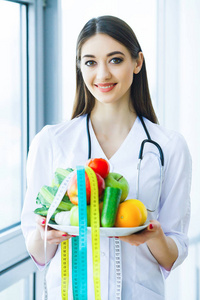 健康。饮食和健康。营养。营养师的医生的肖像与新鲜的水果和蔬菜。美丽的年轻的医生在光室。高分辨率