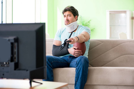 男子颈部和手臂受伤观看美国足球在电视上