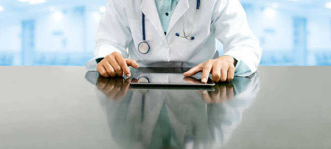 男医生坐在餐桌旁, 用平板电脑在医院办公室。医疗保健人员和医生服务
