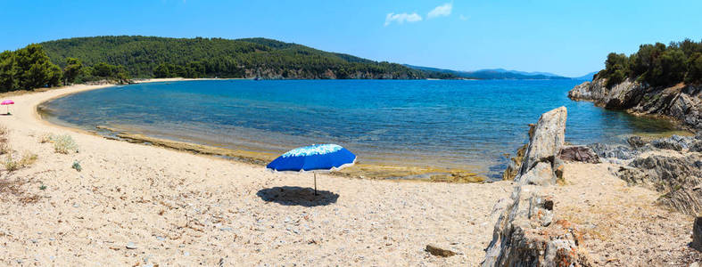 夏季爱琴海海滨景观与沙滩和篷 Sithonia, 哈尔基迪基, 希腊。人们和阳伞的设计是无法辨认的。两个镜头缝合全景