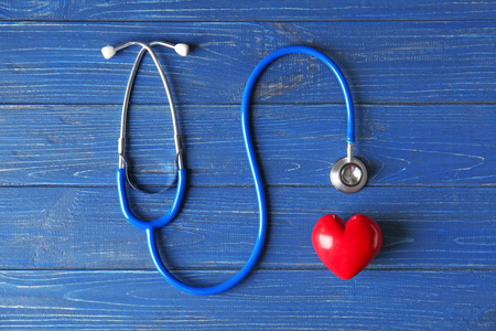 红色心脏和听诊器在木背景。医疗保健理念