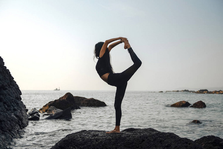 ung frisk kvinna utvar yoga p stranden vid solnedgngen