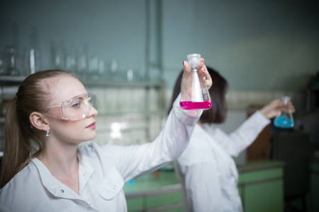 化学实验室里的两名年轻女子拿着烧瓶
