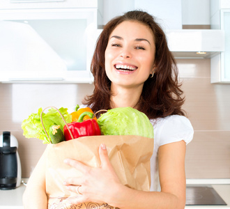 快乐的年轻女人与蔬菜的购物袋。饮食概念