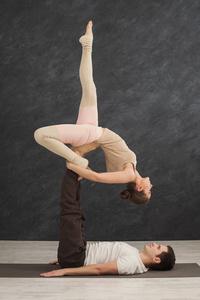 年轻夫妇在垫子上练习 acroyoga