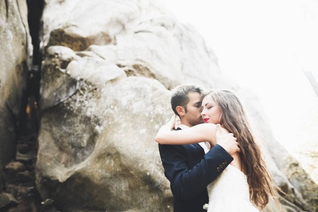 华丽的新娘，新郎亲吻和拥抱附近的悬崖美景