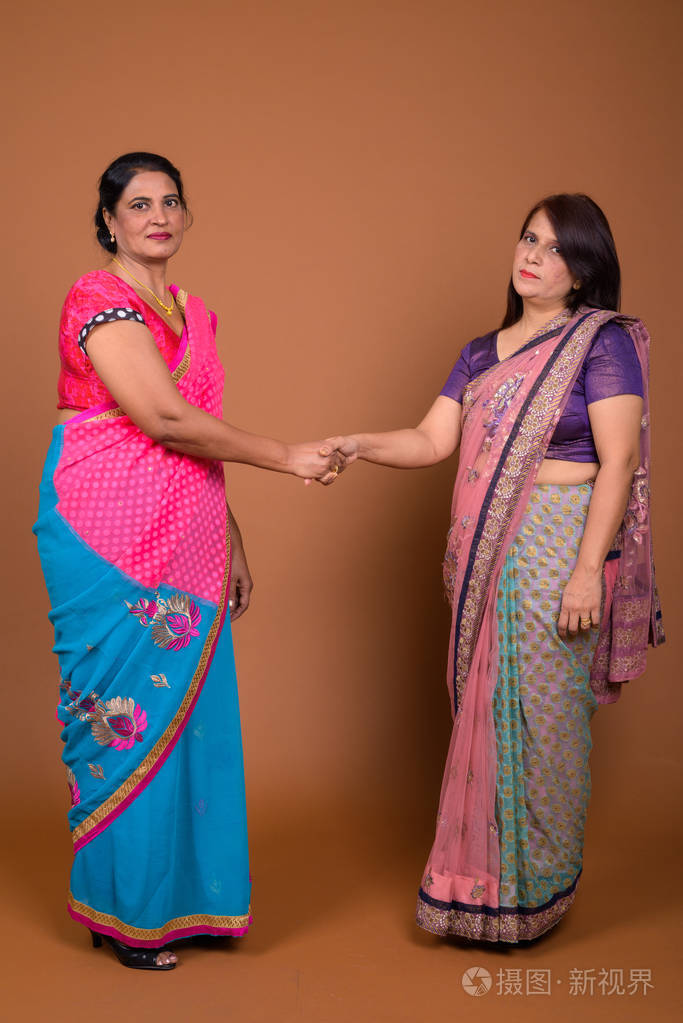 两个成熟的印度妇女握手问候和协议的手