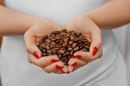 一些新鲜的有机咖啡豆。食品和饮料咖啡的背景。小女孩手中的咖啡豆