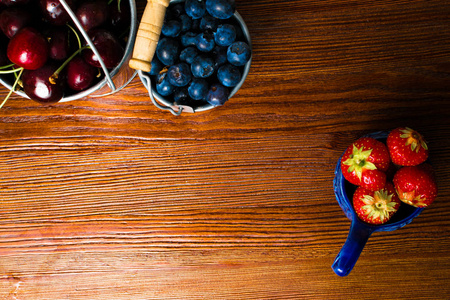 木质背景的浆果。夏天或春天有机浆果在木头在金属桶。草莓, 蓝莓和樱桃在农业, 园艺, 收获概念