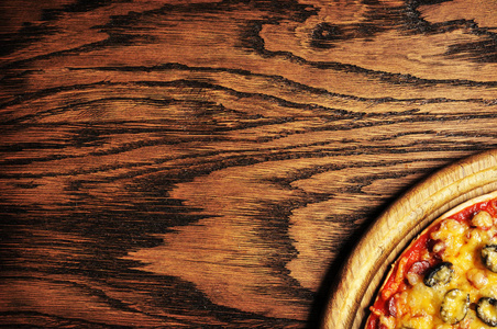 在一个黑色的木质背景上的圆板上美味的意大利比萨的顶级视图