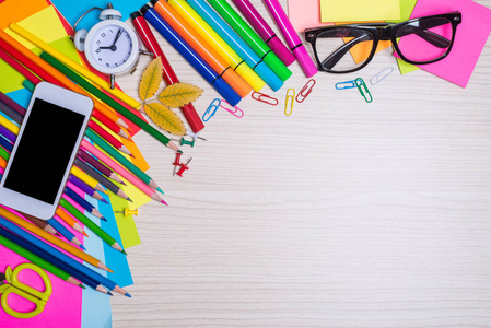 一套学校文具在桌面上的视图。彩色纸, 铅笔, 智能手机在木桌上, 免费空间