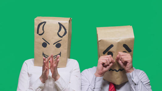 人带着一个包裹在他的头上, 带着一幅画的笑脸哭, 伤心, 和魔鬼嘲笑他