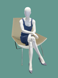 坐着的女模特穿着夏天的蓝色连衣裙, 隔离 n 绿色背景。没有品牌名称或版权对象