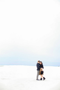 年轻夫妇站在白色的冬季单音背景和拥抱