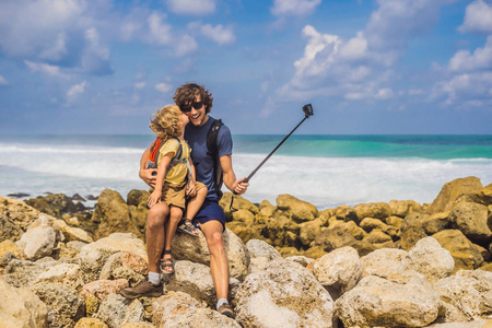 爸爸带着亲吻儿子在惊人的梅拉斯蒂海滩与绿松石水, 巴厘岛, 印度尼西亚