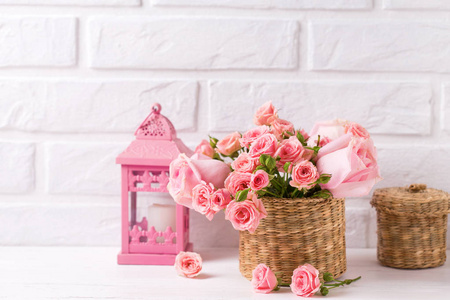 粉红色玫瑰花和装饰品格灯笼反对白色砖墙。花静物。选择性对焦。文本位置