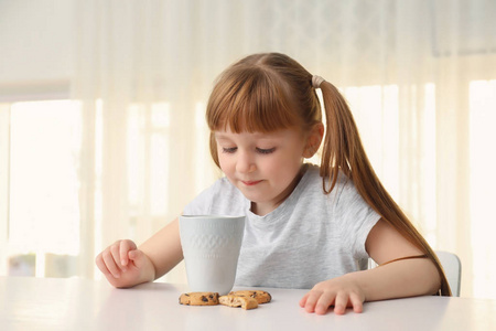 可爱的小女孩与一杯热可可饮料和饼干在家里