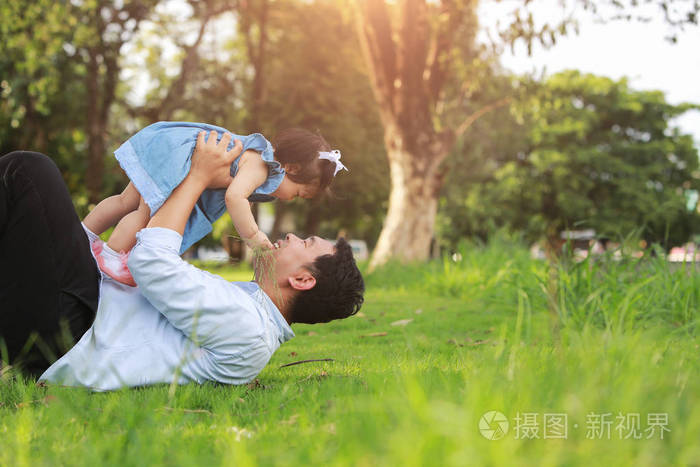 父亲和小女孩玩躺在草地上, 低角度