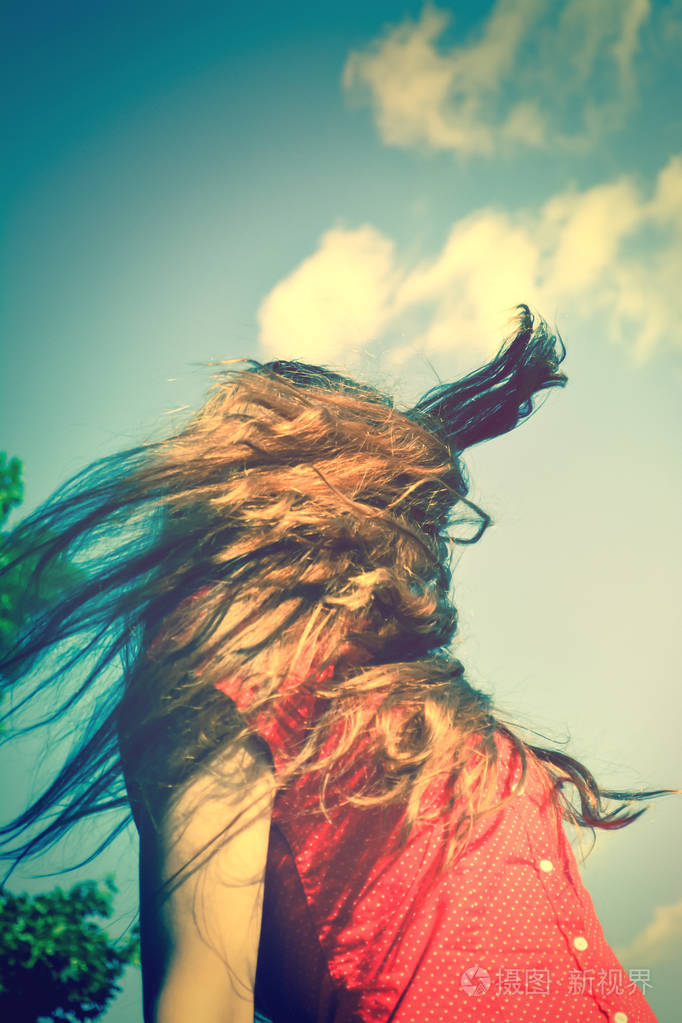 一个年轻的女孩在阳光下长发在风中飘扬一个长着飘着长发的年轻女孩在