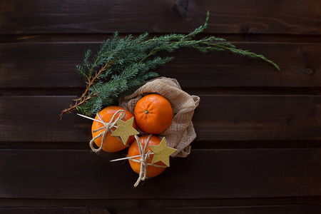 新鲜橙桔与绿色的圣诞树树枝明亮的冬天香味在一个木褐色背景与装饰金星