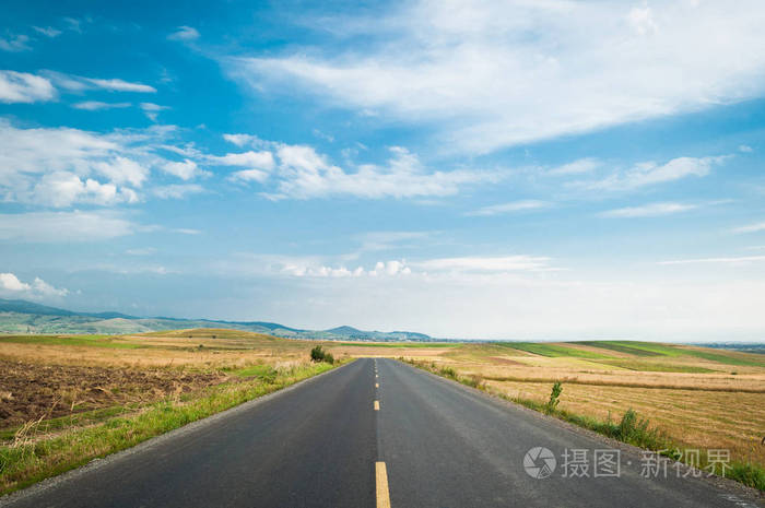 在蓝天下的田野上的一条开阔的道路