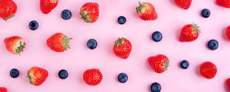 粉红色背景的草莓和蓝莓。浆果图案, 平躺。夏天浆果横幅。创意食品概念