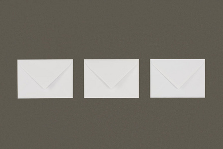 三封闭白色信封的顶视图, 在灰色背景下隔离排列