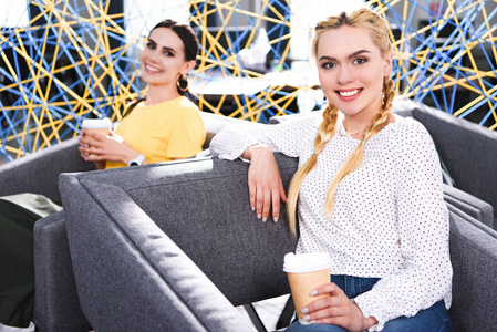 在现代 coworking 办公室, 微笑的女商人与纸杯咖啡