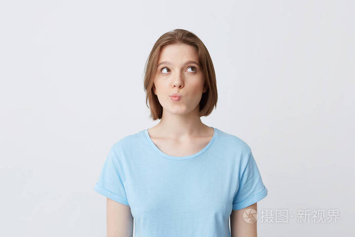 漂亮的年轻女子的画像和感到疑惑孤立的白色背景看着侧面和皱眉她的脸