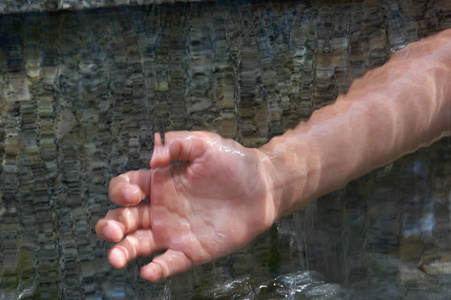 少年的手在流水的梯级下。灰色自然大理石背景与拷贝空间