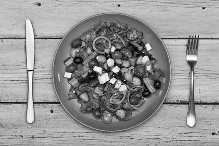黑白照片。希腊沙拉在蓝色的菜。地中海烹饪。餐厅菜单