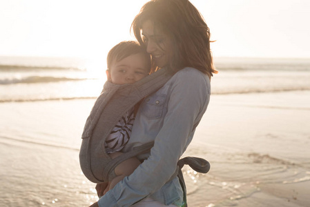 母亲带着 ergobaby 在沙滩上抱着孩子