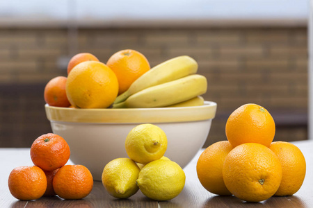 三组柑橘类水果, 柠檬之一, 另一个橘子和橘子, 后面的水果碗里有更多的柑橘水果和香蕉