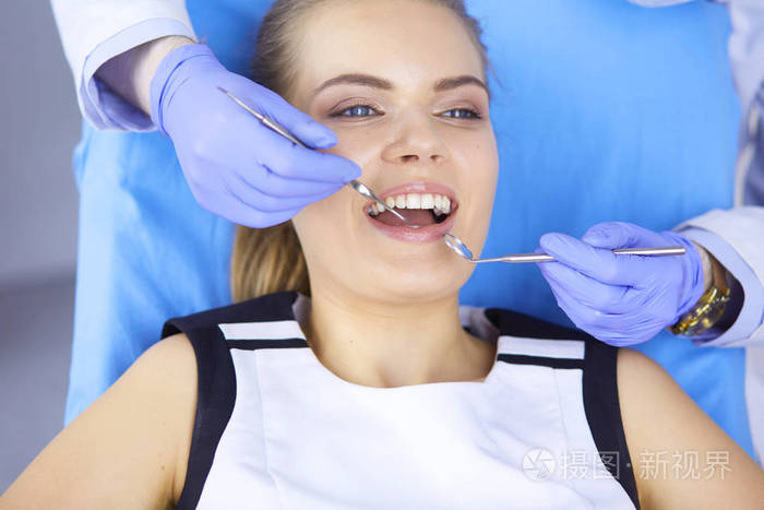 美丽的女孩在牙科椅子上检查牙医