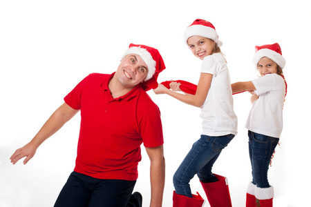 快乐的父亲和两个女儿在笑的圣诞老人的帽子