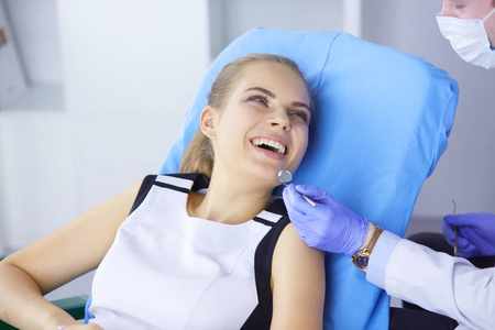 美丽的女孩在牙科椅子上检查牙医