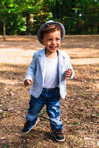 小可爱的男孩的画像在帽子和夹克在公园