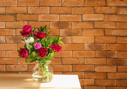 砖墙边桌上有美丽的牡丹花花瓶
