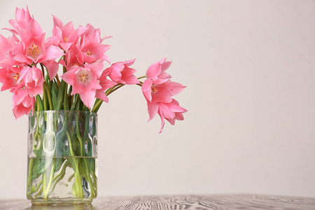 花瓶与美丽的郁金香在木桌反对光背景
