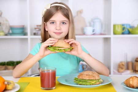 漂亮的小女孩吃漂亮的小女孩,在家里的厨房里吃早餐照片